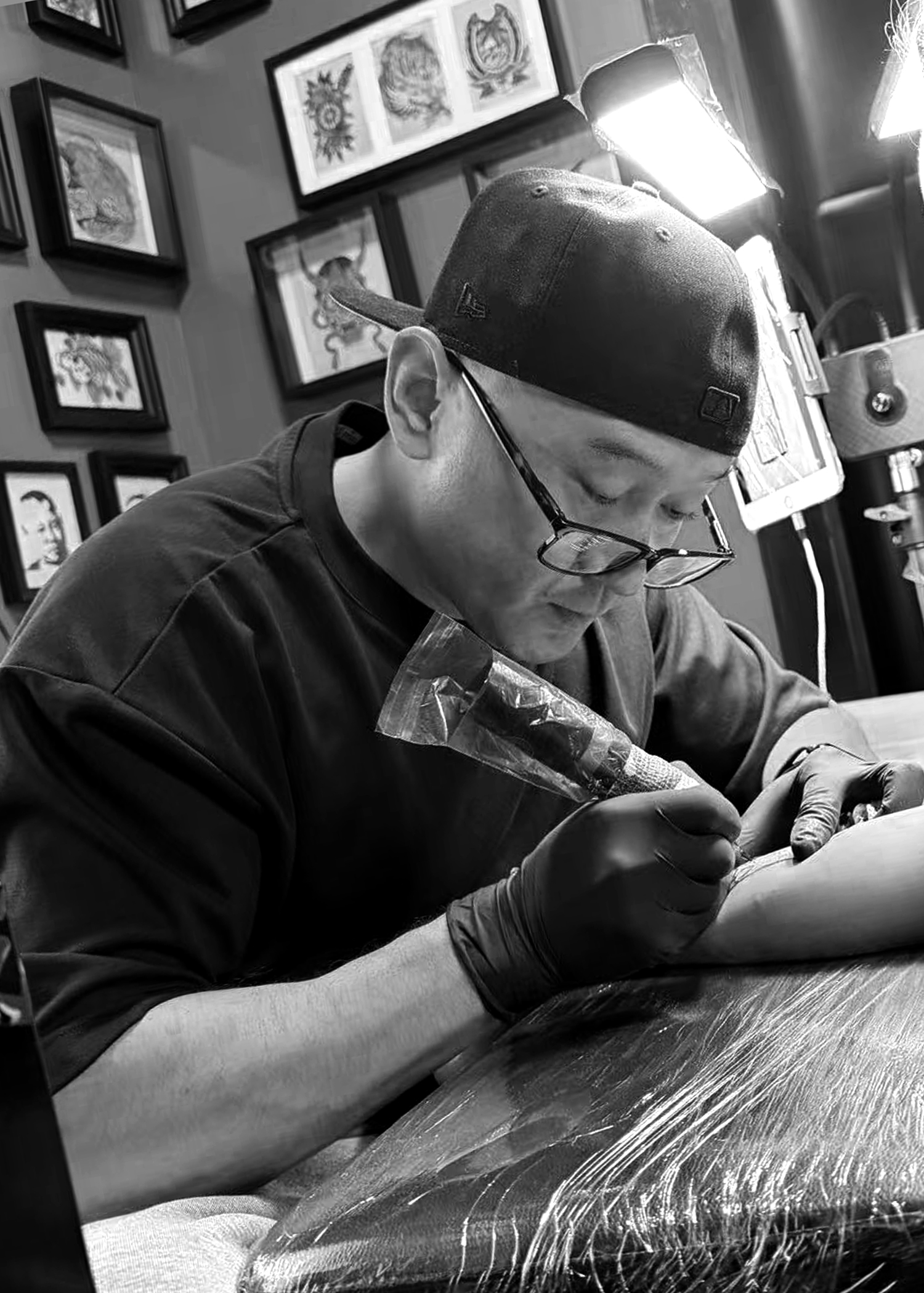 Black and white photo of Jun tattooing at Assassin Tattoo